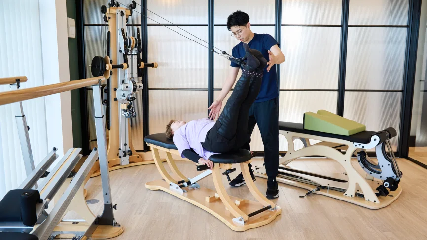 ジャイロトニック®のマシンで運動する利用者とサポートする理学療法士