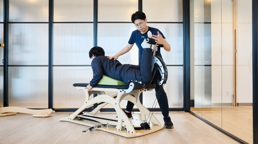 柔軟性と筋力を同時に高める運動をする利用者とサポートする理学療法士