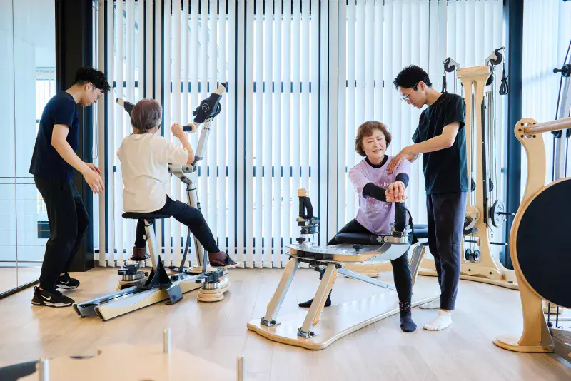 運動する複数の利用者とサポートする理学療法士