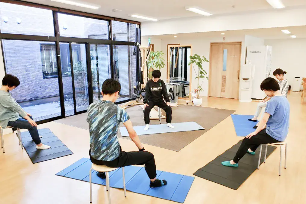 マットを引いて運動する利用者と理学療法士