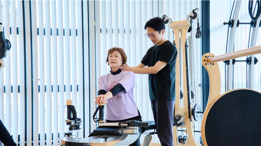 ジャイロトニック®による運動療法を受ける利用者とサポートする理学療法士