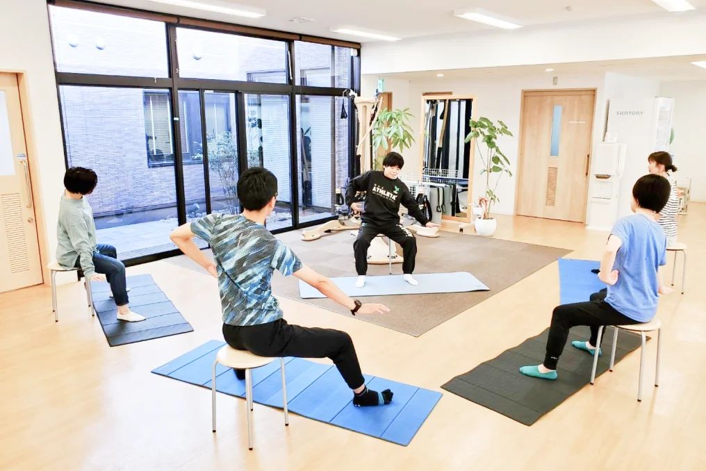 シニア向けのグループで運動する利用者と指導する理学療法士