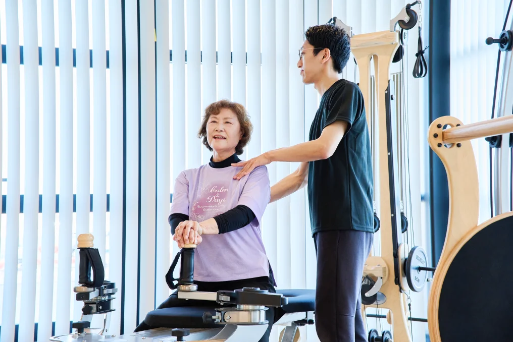 姿勢改善のトレーニングをする女性とサポートする理学療法士