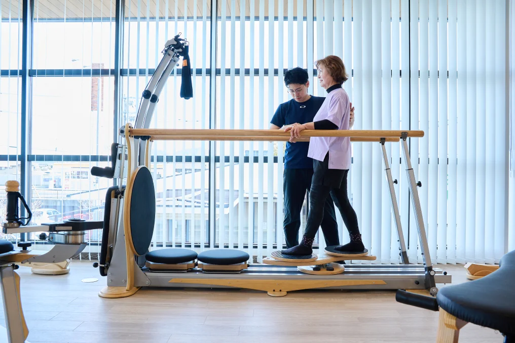 O脚・X脚改善のトレーニングをする女性とサポートする理学療法士