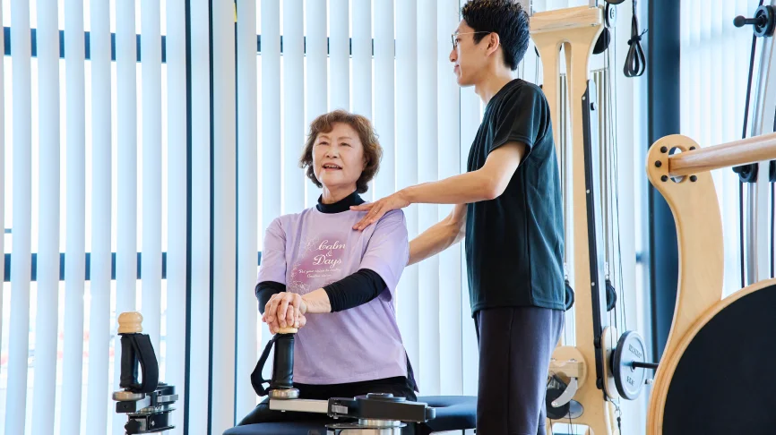 ジャイロトニック®による全身運動する女性とサポートする理学療法士