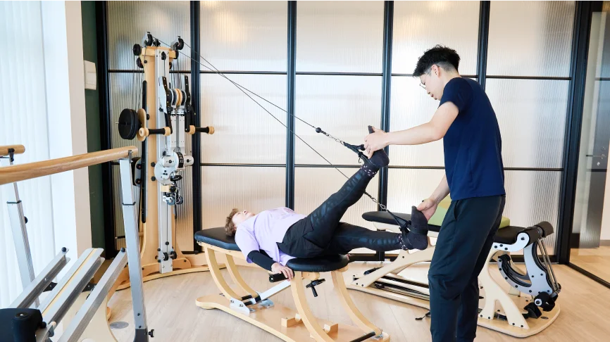 ジャイロトニック®による運動療法をする女性とサポートする理学療法士