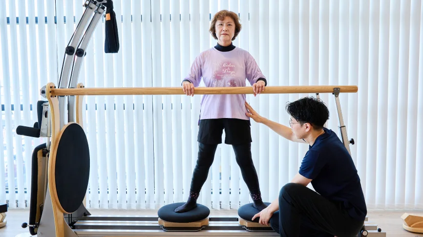 バランストレーニングをする女性とサポートする理学療法士