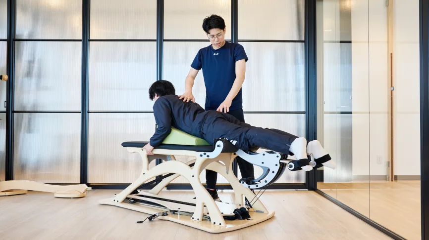 ジャイロトニック®によるパーソナルトレーニングをする女性とサポートする理学療法士